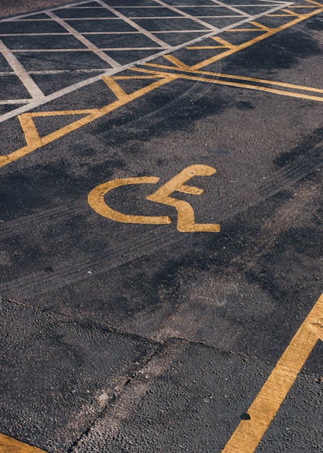 Close-up view of a numbered parking space in an asphalt driveway, with the number '22' painted in white. The parking area is part of a residential or commercial property, featuring faint yellow lines