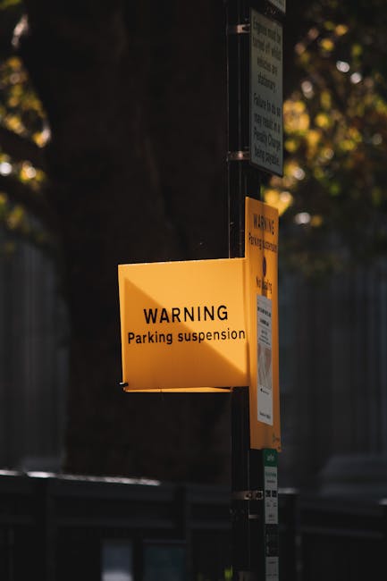 A close-up view of a rectangular metal 'No Parking' sign with gold lettering and a decorative border, mounted on a light green wooden wall composed of vertical panels. The sign is centrally positioned